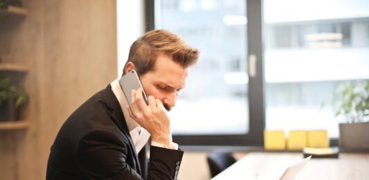 man having a phone call in front of a laptop