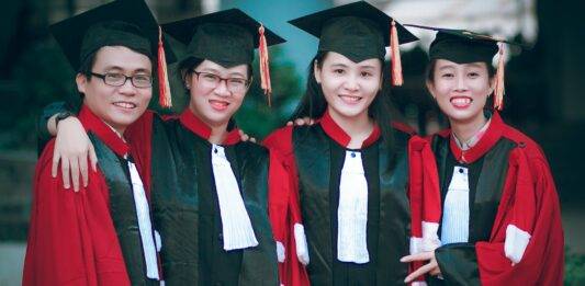 man and women wearing red and black academic gowns and black mortar boards